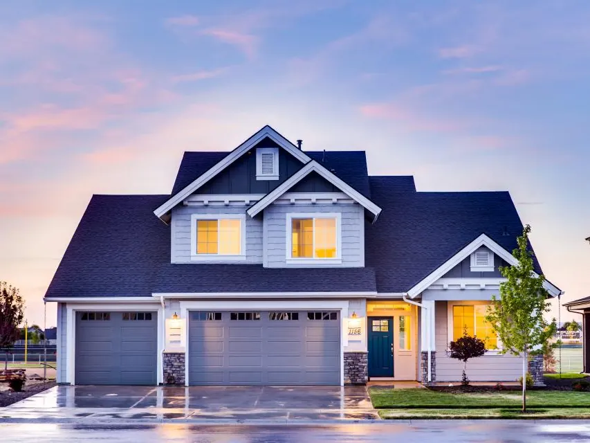Two-story family home with warm lights on at dusk
