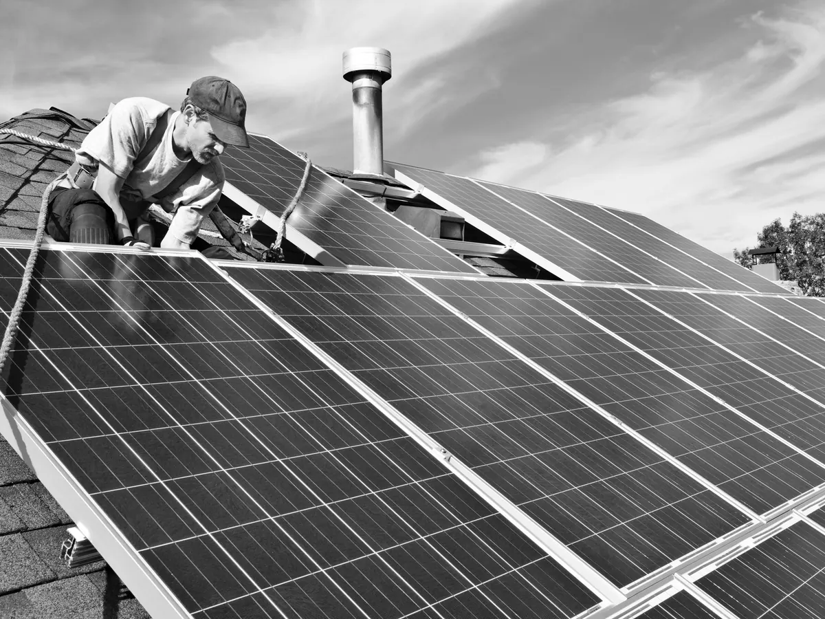 Installer fitting solar panels on a residential roof