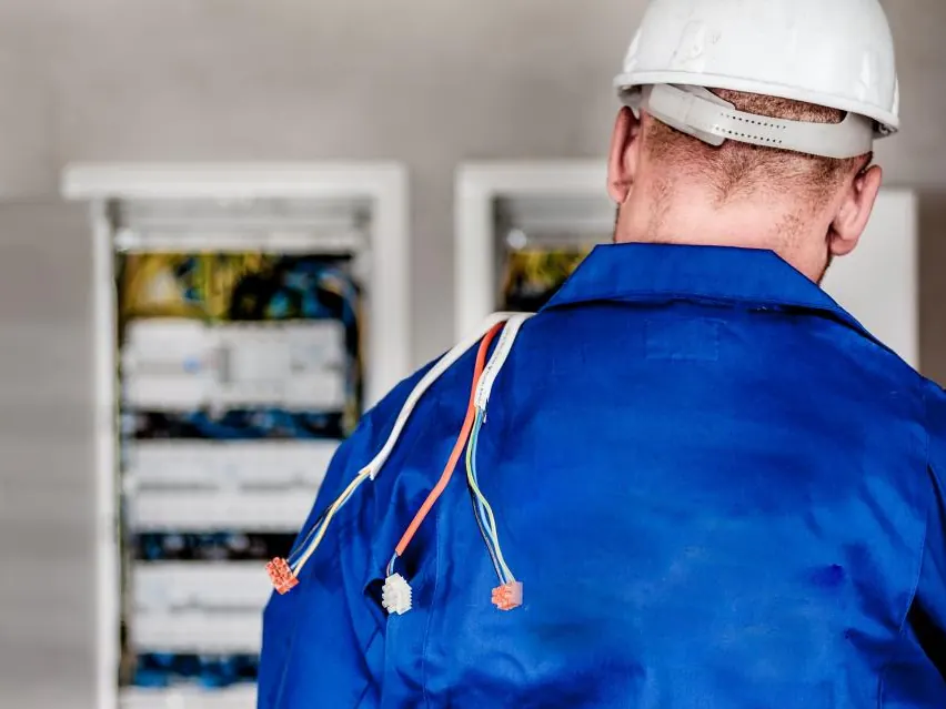Technician in a hard hat working at an electrical cabinet
